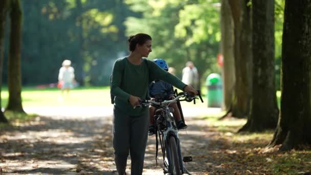 Mor Som Bär Cykel Utomhus Parken Med Barn Baksätet Cykel — Stockvideo