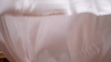 Dışarıda battaniyeyi sallayan kadın çarşaftaki tozu kaldırıyor.