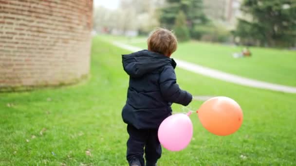 風船を持って外に走っている幸せな小さな男の子 — ストック動画