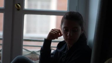 Düşünceli kadın pencereden dışarı bakarak hayatı düşünüyor. Oturduğu daireden dışarı bakıyor.