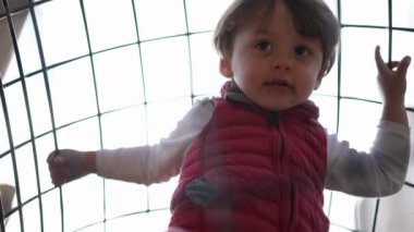 Küçük çocuk oyun sahasında ayaklarının altında oyun yapısında oynuyor