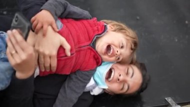 Mutlu anne ve çocuk birlikte dışarıda gülüyor ve birlikte gülüyorlar.