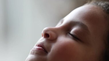 Çocuk tefekkür ederken gözlerini kapatıyor. Çocuk gülümseyerek gökyüzüne bakıyor.