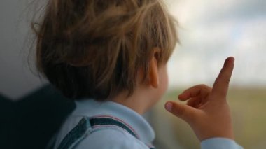Düşünceli küçük çocuk bir yolculukta trenin camından dışarı bakıyor kırsal bölgeyi görüyor
