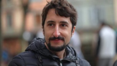 Dışarıdaki kameraya gülümseyen genç adam portresi.