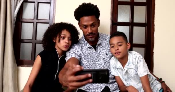 アフリカの父親は自宅で子供とスマートフォンのデバイスをチェック — ストック動画