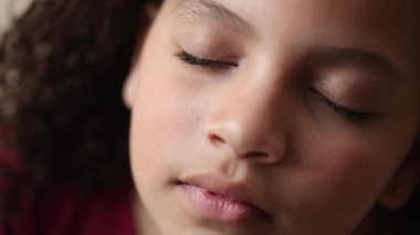 Küçük kız gülümseyen gözlerle gökyüzüne bakıyor. Çocuk umutla ve inançla yukarı bakıyor.