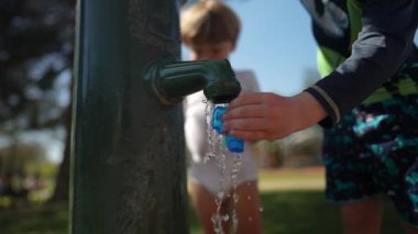 Oyuncak silahı musluktan suyla dolduran çocuk elleri