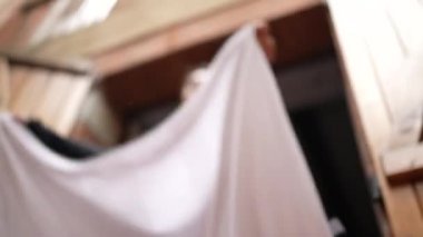 Çarşaf tozunu silkeleyen kişi. Evi temizleyen kadın dışarıda battaniye sallıyor.