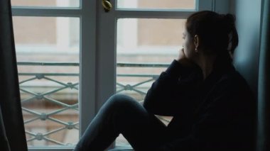 Pencere kenarında oturan düşünceli kadın dışarı bakıyor. melankolik kişi