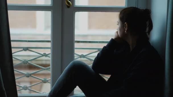 Eine Zierliche Frau Die Fenster Sitzt Und Nach Draußen Schaut — Stockvideo