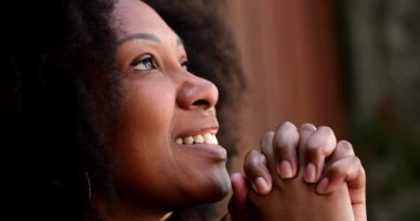 Afrikalı kadın, dua ederken gözlerini kapatıyor.