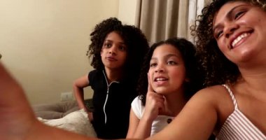 Anne ve çocuklar telefonlarıyla selfie çekiyorlar.