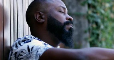 Stresli siyah bir adam yerde oturmuş endişeli.