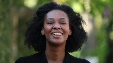 Afrikalı kadın dışarıda kameraya bakıyor.