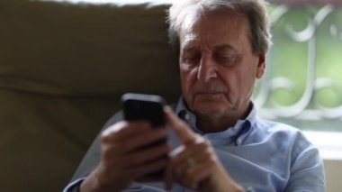 Akıllı telefon kullanan yaşlı bir adam, evden çalışan yaşlı bir iş adamı.