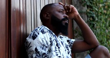 Şaşkına dönmüş Afrikalı bir adam yerde oturmaktan endişeli.