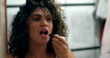 Latin Latin asıllı. Banyodaki aynanın önüne ruj sürüyor. Dışarı çıkmaya hazırlanıyor.