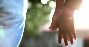 Arka planda güneş ışığının parlamasıyla birleşen ellerin yakın çekimi. İki aşık arasındaki güzel romantik an