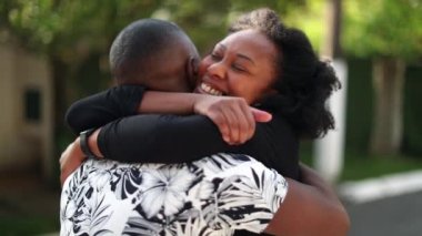 Siyah çift mutlu bir kavuşma, iki insan sarılıp öpüşüyor.