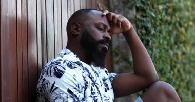Şaşkına dönmüş Afrikalı bir adam yerde oturmaktan endişeli.