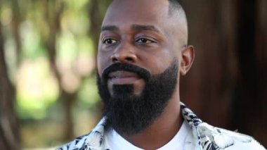 Rahatlamış Afrikalı adam dışarıda gülümsüyor. Kendine güveniyor.