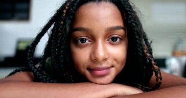 Latin kökenli siyahi kız çocuk portresi. Kameraya yakından bakıyor.