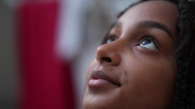 Dalgın siyah kız çocuğu, yakından gökyüzüne bakıyor.