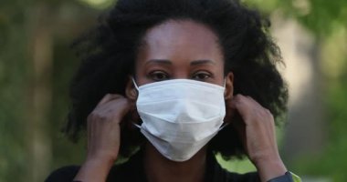 Afrikalı kadın kabarık yüzlü maskesini çıkarıyor.