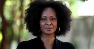 Afrikalı siyahi kadın portresi dışarıda kameraya bakıyor.