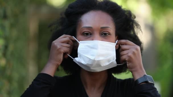 Covid 19フェイスマスクをしたアフリカ人女性 黒の女性は外科マスクを置く — ストック動画