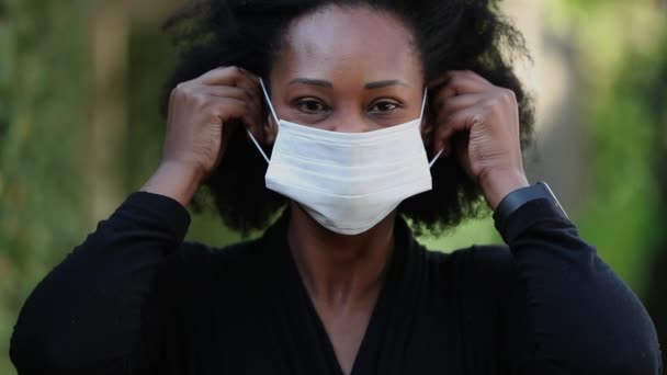 Covid 19フェイスマスクをしたアフリカ人女性 黒の女性は外科マスクを置く — ストック動画