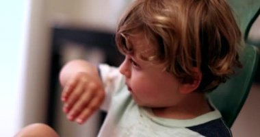 Çocuk sümük burnunu eliyle siliyor.