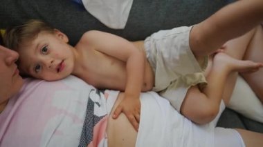 Anne ve çocuk kanepede uzanmış, dinleniyor. Küçük çocuk annesiyle birlikte kanepede yatıyor.