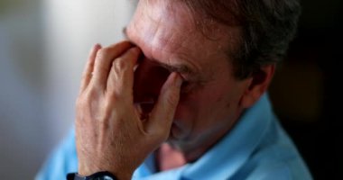 Endişeli biri, endişeli yaşlı bir adam gözlerini ovuşturuyor.