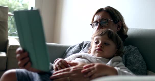 Avó Segurando Criança Colo Enquanto Estiver Usando Dispositivo Tablet Sentado — Vídeo de Stock