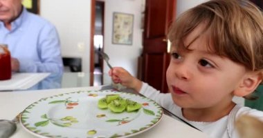 Çocuk kivi meyvesi yiyor. Küçük çocuk meyveli tatlı yiyor.