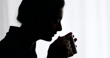 Siluet insan sabah kahvaltısında çay ya da kahve içiyor.