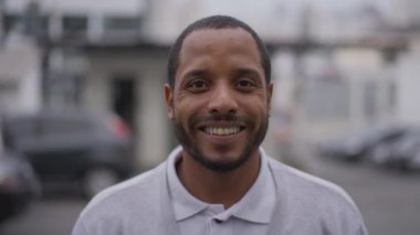 Mutlu Afrikalı Amerikalı genç adam gülümseyen kameraya bakıyor. Brezilya 'lı bir Güney Amerikalı sokak ortasında dikiliyor.