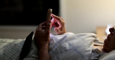 Yatakta uzanmış akıllı telefonlara bakıyor, yaşlı kadınlar geceleri telefon kullanıyor.