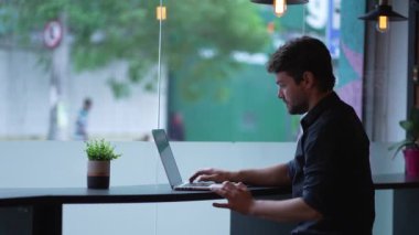 Genç adam dizüstü bilgisayarı açıyor. Şehir kaldırımlarında uzaktan kumandayla çalışıyor. Modern teknoloji aygıtı kullanan kişi