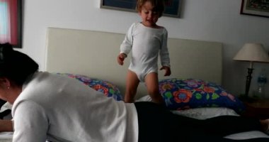 Bebek yatakta zıplayıp oynuyor. Çocuk sevinçten zıplayacak