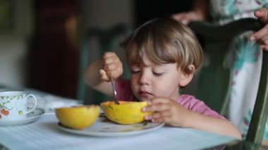 Küçük bebek kaşıkla papaya meyvesi yiyor.