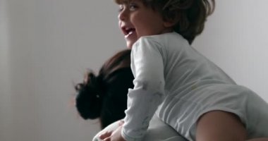 Mutlu bebek anne sırtında gülüyor ve gülümsüyor.
