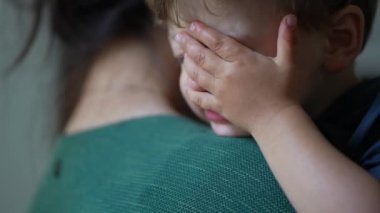 Anne kucağında ağlayan küçük çocuk gözyaşlarını siliyor.