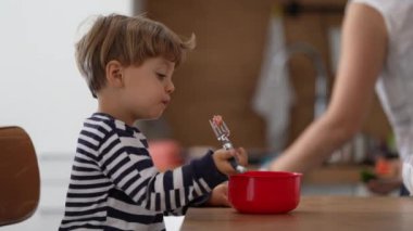 Düşünceli çocuk çatalla çilekli atıştırmalık yiyor.