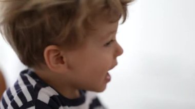 Küçük bir çocuk başını ve saçlarını sallıyor..