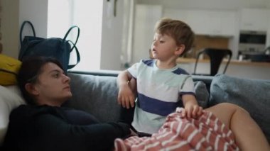 Anne ve küçük çocuk evdeki kanepede rahat ve gerçek hayatta oturuyor.
