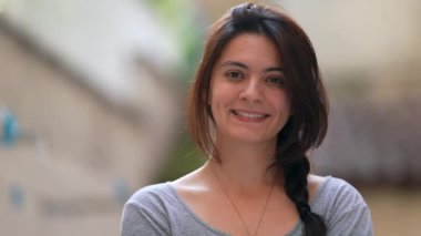 Dışarıda kameraya gülümseyen 30 'lu yaşlardaki bir kadının portresi.