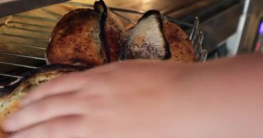 Baker fırından ekmek çıkarıyor ve raflara diziyor.